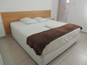 圣保罗Hotel Ourinhos - Centro de São Paulo - Próximo 25 de Março e Brás - By Up Hotel的一张铺有白色床单的床和一张棕色的毯子