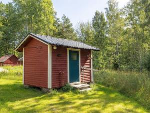 HjortedChalet Mjöshult - SND157 by Interhome的一块红小棚子,在田野里有一扇蓝色的门