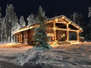 罗瓦涅米北极圈湖假日酒店的雪中带圣诞树的小木屋
