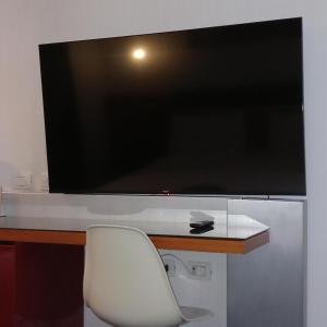 罗马诺富特罗马欧酒店的一张带白色椅子的桌子上的大屏幕平面电视