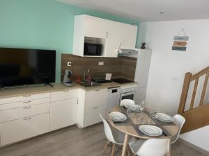 马耶讷L'Atypique ,maison individuelle Wifi et Netflix gratuit的厨房配有桌椅和电视。