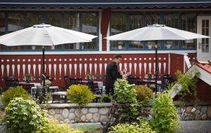 塔尔伯格阿克布拉德斯加斯特吉维瑞水疗酒店的站在餐厅前,拿着桌子和遮阳伞的人