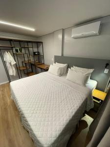 大坎皮纳Hotel do Vale的卧室配有一张带白色床单和枕头的大床。