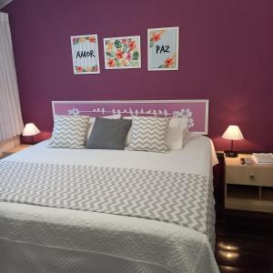 布希奥斯Apart Coração de Búzios的一间卧室配有一张大床和紫色墙壁