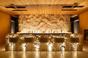 弗洛里亚诺波利斯Fuso Concept Hotel的石头墙前带凳子的酒吧