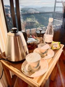 马尼萨莱斯Atardeceres del Cafe的一张带餐具和茶壶的木桌和窗户