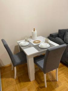 克鲁舍瓦茨Apartman Breza 3的餐桌、两把椅子和一张带板子的白色桌子