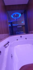 贝洛奥里藏特莫泰幻想3情趣酒店（仅限成人）的浴室设有白色浴缸,享有蓝色的灯光