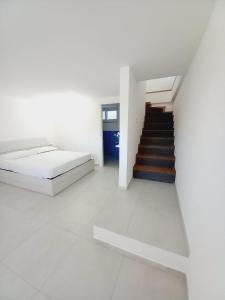 伊斯基亚Marintò Apartaments的一间白色的卧室,配有床和楼梯