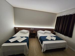 大坎普HOTEL CAMPO GRANDE的一间设有两张床铺和毛巾的房间