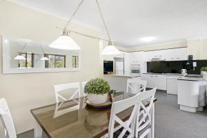 黄金海岸Oceanside Cove的厨房以及带玻璃桌和白色椅子的用餐室。