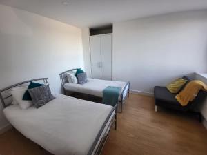 巴塞尔顿Vetrelax Basildon City Center Apartment的一间设有两张床、一张沙发和一把椅子的房间