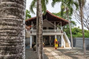 塔马林多Mai Ke Kai Surf House的前面有棕榈树的房子