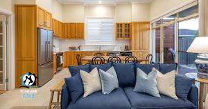维克多港Seaspray Cottage Holiday Accommodation Victor Harbor的一间带蓝色沙发的客厅和一间厨房