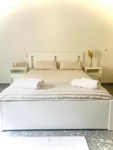 Áno ViánnosPLANTZOUNAKIS的配有两张桌子的房间的一张白色床