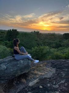 达瓦拉维Big Game - Udawalawe by Eco Team的坐在岩石上观看日落的女人