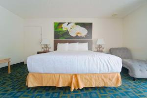 印地欧Royal Plaza Inn的卧室配有一张白色大床和一把椅子