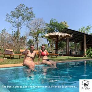 锡吉里亚The Cottage Sigiriya的两个穿着泳衣的女人坐在游泳池里