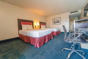 印地欧Royal Plaza Inn的酒店客房带两张床、一张桌子和椅子。