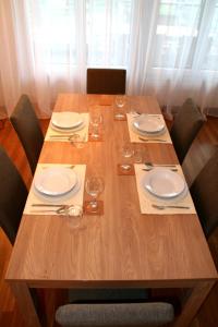 楚格Nest - Baarerstrasse 55的一张木桌,上面放有盘子和酒杯
