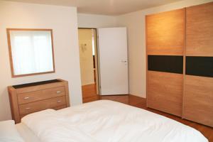 楚格Nest - Baarerstrasse 55的卧室配有白色的床和木制梳妆台。