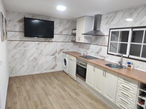 Rua da Avó的一间厨房,配有白色橱柜和墙上的电视