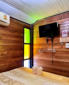 三帕兰MrT Riverside Sampran มิสเตอร์ที โฮมสเตย์-ช้องนาง的木墙上设有平面电视的房间