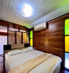 三帕兰MrT Riverside Sampran มิสเตอร์ที โฮมสเตย์-ช้องนาง的一间卧室设有两张带木墙和窗户的床。