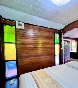 三帕兰MrT Riverside Sampran มิสเตอร์ที โฮมสเตย์-ช้องนาง的一间卧室设有两张床和彩色玻璃窗。