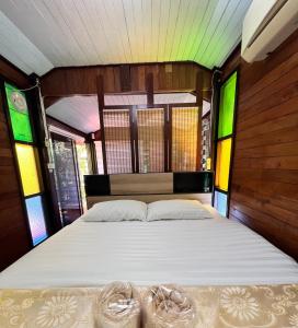 三帕兰MrT Riverside Sampran มิสเตอร์ที โฮมสเตย์-ช้องนาง的一张大床,位于带彩色玻璃窗的房间里