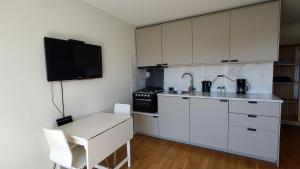 利勒桑Kaldvell Apartman的厨房配有白色橱柜、桌子和电视。