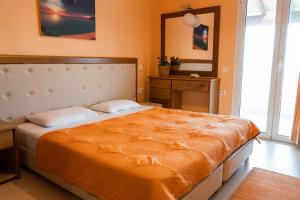 圣斯特凡诺斯Antheia Apartments的一间卧室配有一张带橙色毯子的大床