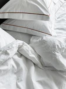 德鲁斯基宁凯Mana Sleep & Spa的一张带白色床单和枕头的未铺好的床