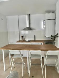 赫雷斯-德拉弗龙特拉SHERRY SUITES VIII Apartamentos PARKING GRATUITO的厨房配有木桌和白色橱柜。