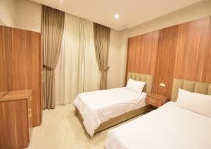 科威特الدرة للشقق الفندقية的酒店客房设有两张床和窗户。