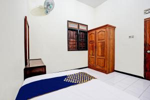 TubanOYO Life 92785 Wisma Trubus Syariah的一间卧室配有一张床和一个木制橱柜