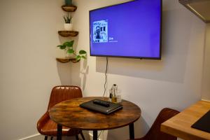 克罗伊登Stylish centrally-located studio with parking的一间房间,墙上设有一张桌子和一台电视