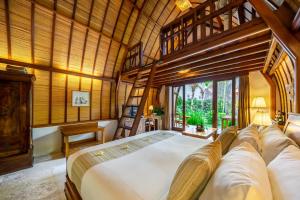 沙努尔Klumpu Bali Resort的一间带一张大床的卧室,位于一个拥有木制天花板的房间