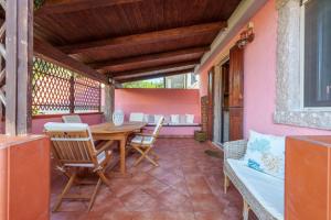 阿列恩图Casa Baia Vignola的粉红色房子内带木桌和椅子的庭院
