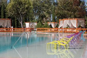 伊斯坦布尔伊斯坦布尔阿塔科尤喜来登酒店的一个带黄色桌椅的游泳池和一个水库