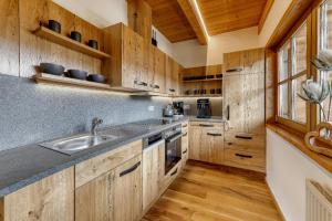 茨维泽尔Chalet Leithenwald的一个带木制橱柜和水槽的厨房