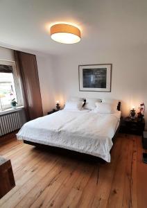 巴特萨尔茨乌夫伦Unter der Linde 1的卧室配有一张白色大床,铺有木地板