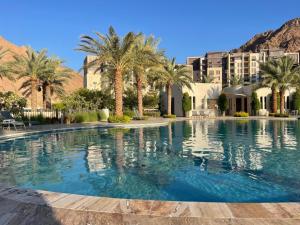 亚喀巴aladnan apartment alraha village的一座棕榈树和建筑的大型游泳池
