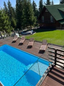 穆恩特勒白索利Transylvania Villa & Spa的一个带甲板和椅子的游泳池以及一座房子