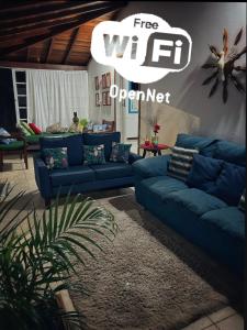 帕拉蒂Casa aconchegante em bairro nobre da cidade Paraty的客厅配有蓝色的沙发和标志性免费WiFi操作员