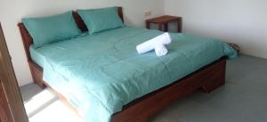 特特巴图Tetebatu Fullmoon的一张带绿色被子的床和两个枕头