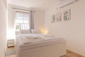 米科瓦伊基Agamim Apartments的白色的卧室设有一张白色大床和一个窗户。