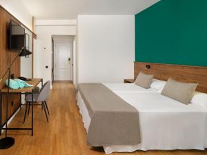 拉克鲁斯FERGUS Puerto de la Cruz的一间卧室配有两张床、一张桌子和一台电视。