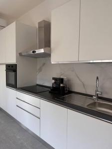 科莫Appartamento Dolce Vita - Parking & Self Check-in的厨房配有白色橱柜和黑色台面
