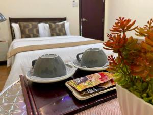 圣何塞Hillside Hotel的一间卧室配有床和一张桌子及两个茶杯